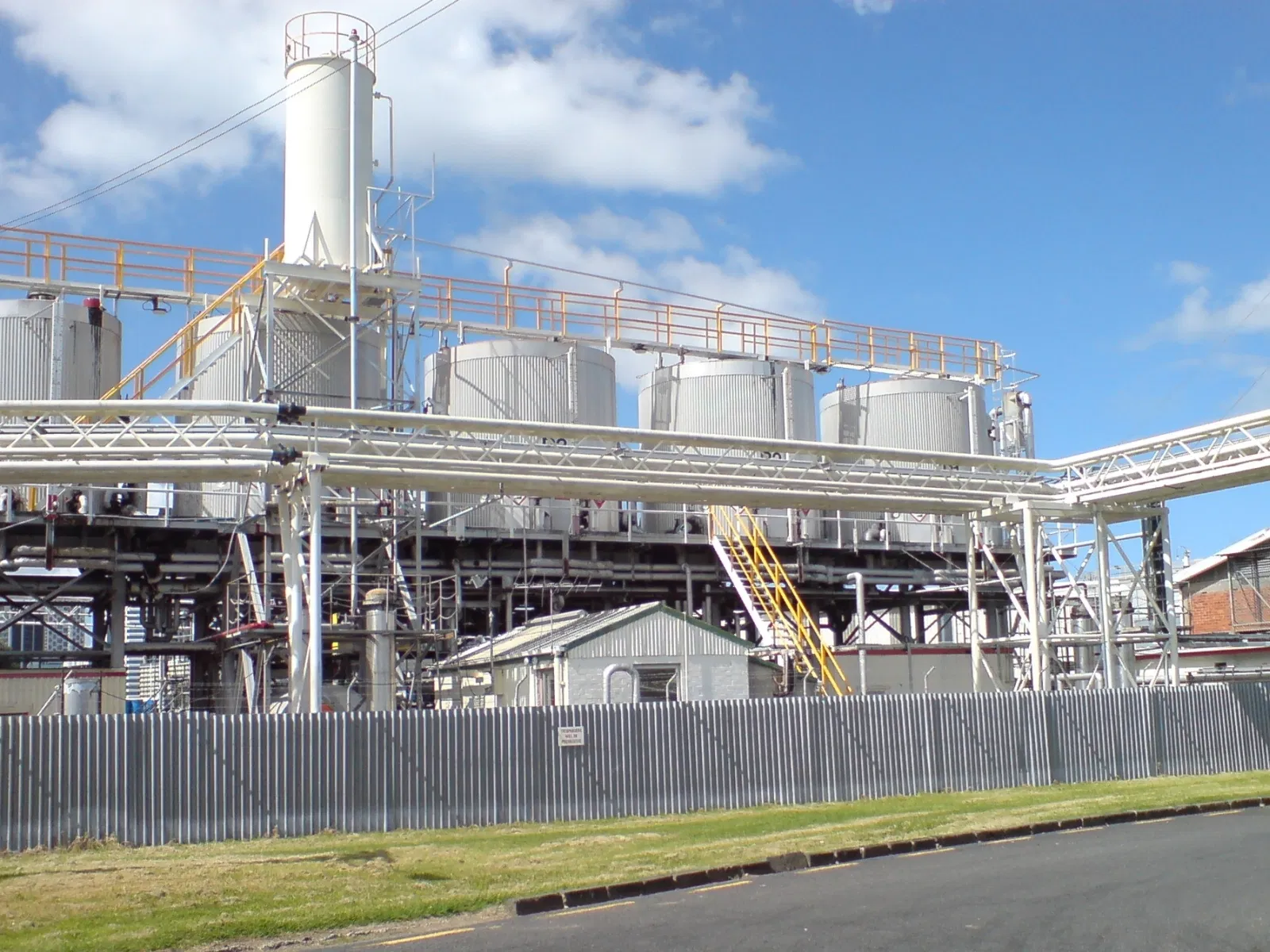 Chemical plant with large storage tanks, elevated pipework, and industrial processing equipment.