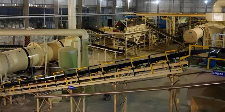 Conveyor belts, rotary dryers, and processing machinery inside a phosphate chemical processing facility