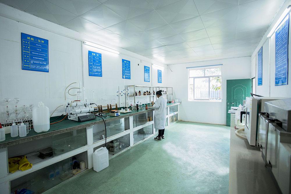 Technicien de laboratoire travaillant dans une installation de contrôle qualité et réalisant une analyse chimique d'échantillons d'acide phosphorique