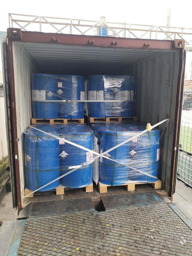Fûts bleus palettisés, enveloppés dans un film plastique et sécurisés par des sangles d'arrimage à l'intérieur d'un conteneur maritime pour expédition à l'export