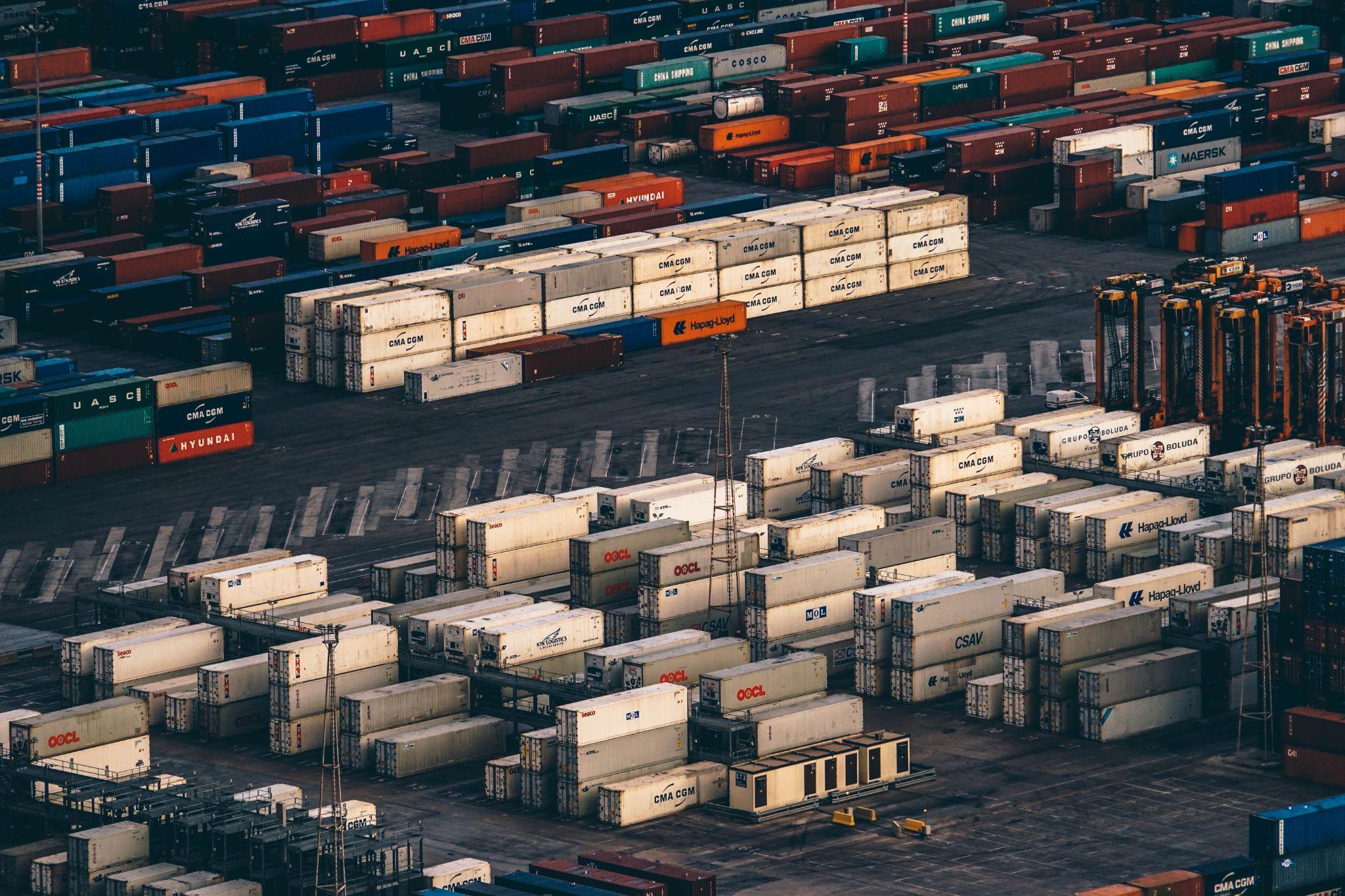 Rows of colorful shipping containers at an international cargo port, representing customs classification and chemical export logistics.