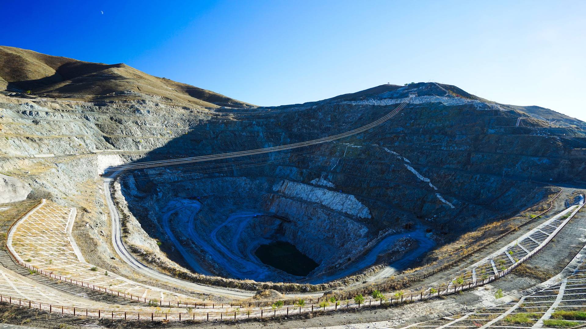 Huge deep open-pit phosphate mine under clear blue sky showing extensive excavation