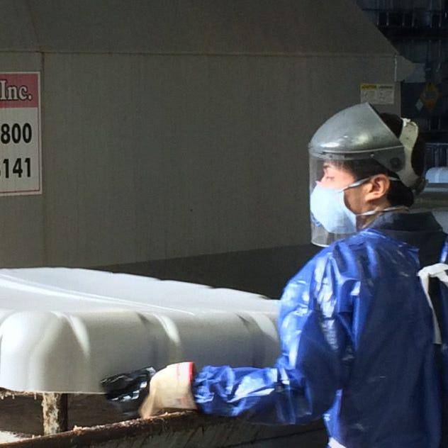 A faceless Asian factory worker in protective gear inspecting industrial equipment, representing quality control. 