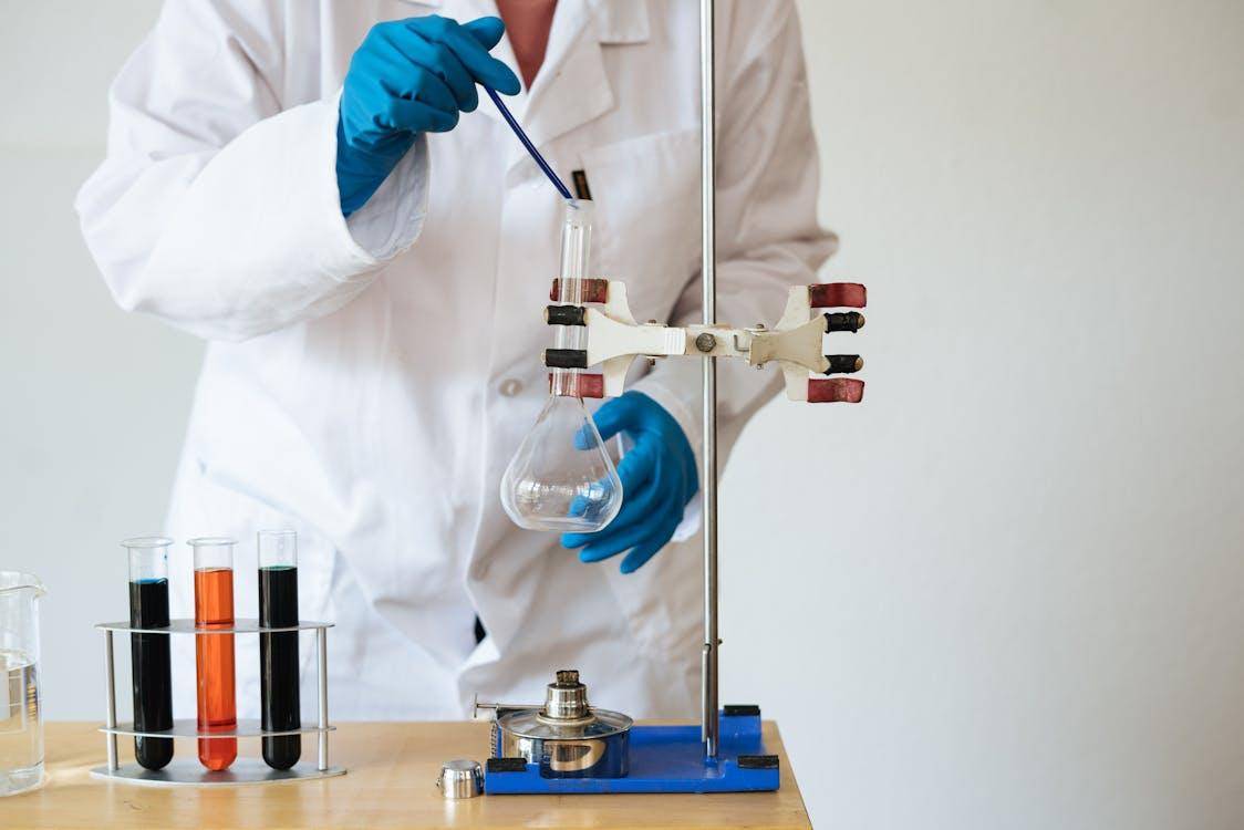 A faceless Asian scientist conducting precise chemical analysis in a modern laboratory.