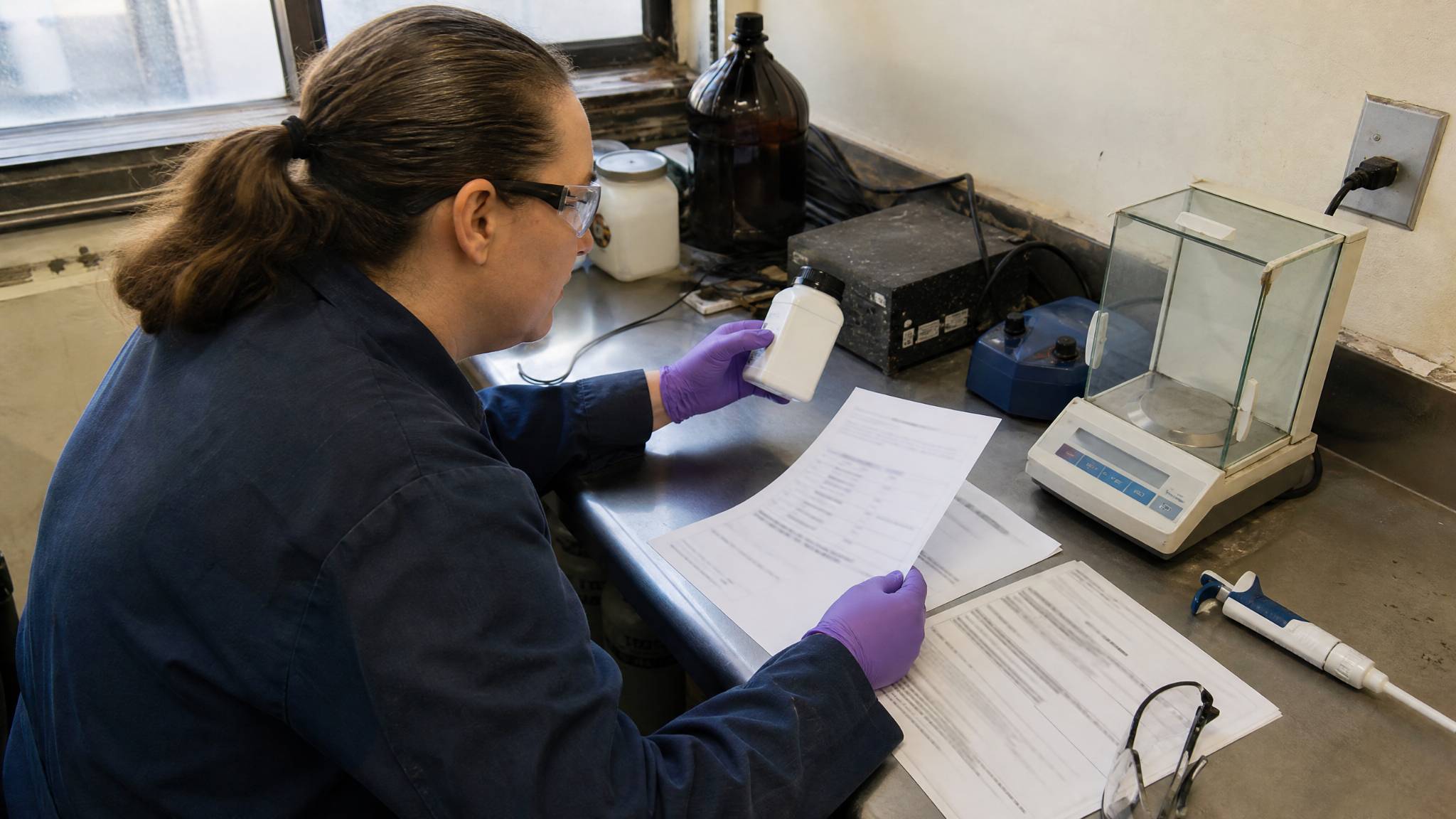 Laboratory technician reviewing phosphoric acid quality documents and a product sample.