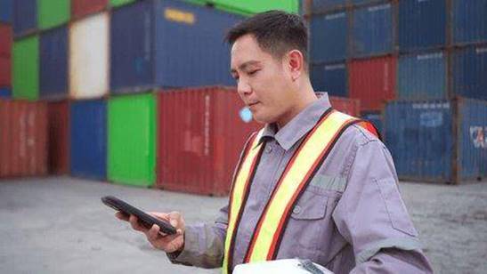 Phosphoric Acid vs Oxalic Acid 6 An Asian Chinese male logistics manager in a high-visibility vest standing in front of stacked shipping containers at a busy international port.