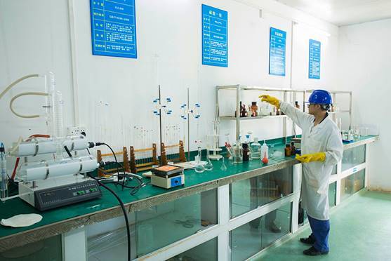 Un technicien travaille dans un laboratoire de contrôle qualité d’acide phosphorique avec des équipements d’analyse et des zones de travail identifiées.