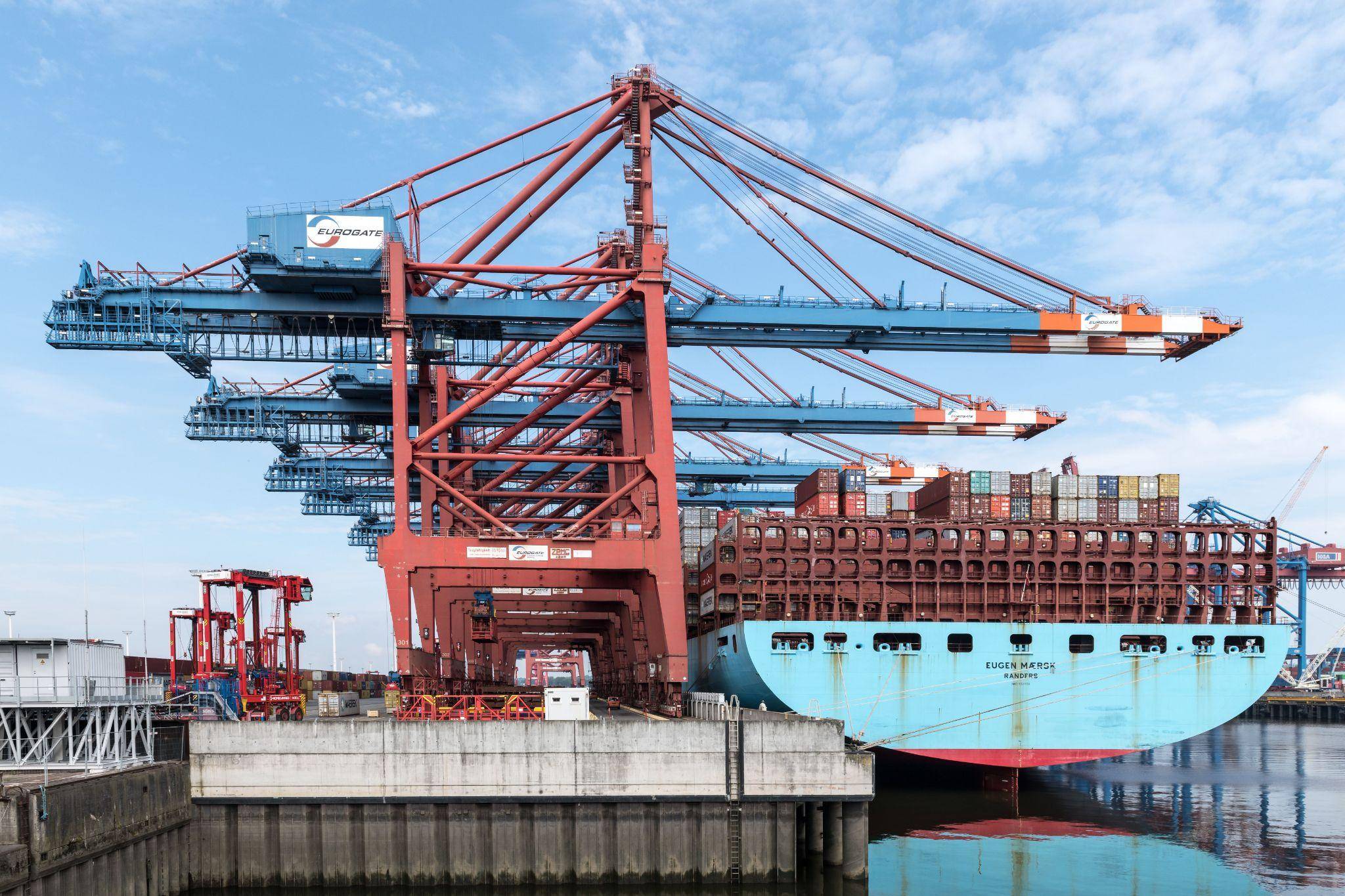 Container ship being loaded by port cranes during an international chemical shipment